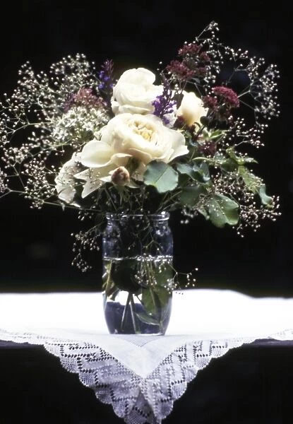 Old fashioned posy of full blown roses and gypsophila aganst dark background credit