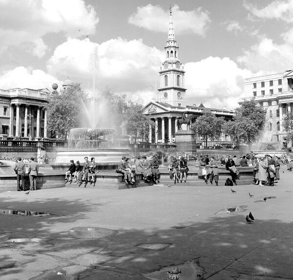 People around the fountains in Trafalgar Square with St. Magnus the Martyr in background