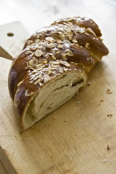 Piece of sweet, yeast bread with almonds and almond paste on wooden board credit