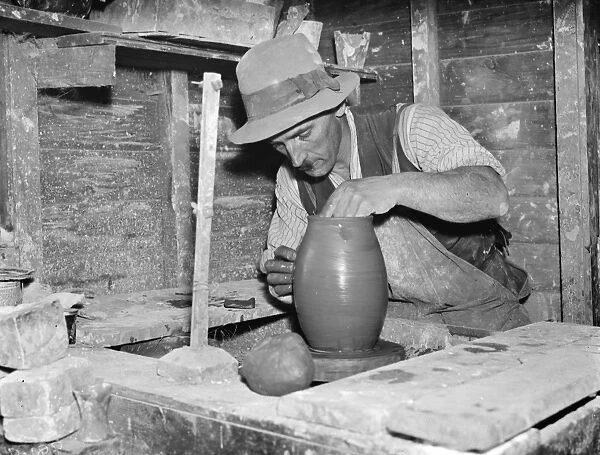 Pottery maker Mr Sadler moulding clay on a potters wheel. 1938
