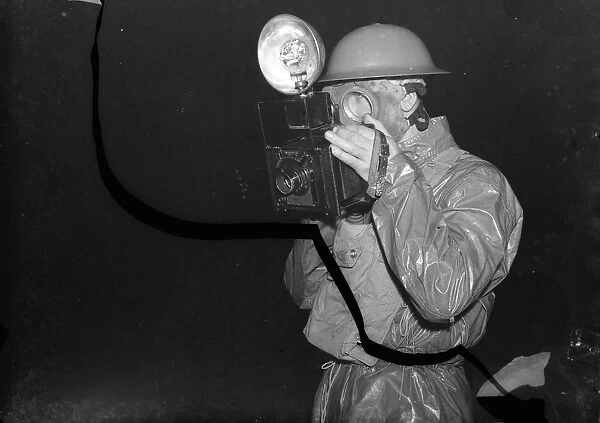 A press photographer in a ARP ( Air Raid Precautions ) gas suit, taking pictures