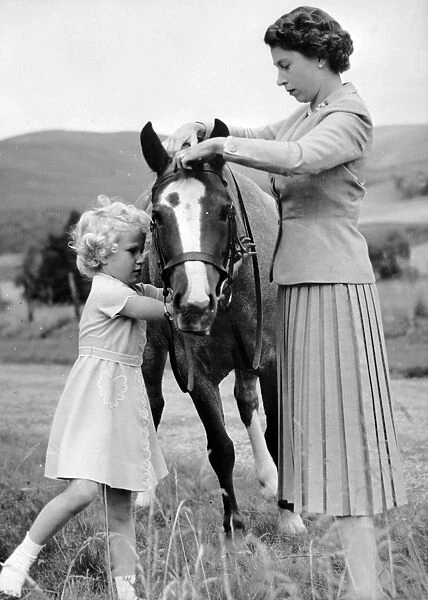 Princess Anne helps her mother Queen Elizabeth to adjust the bridle of the pony Greensleeves