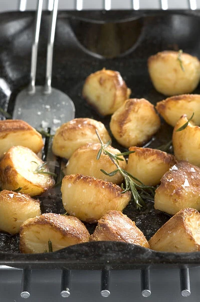 Roast potatoes in black roasting tin with salt and rosemary credit: Marie-Louise