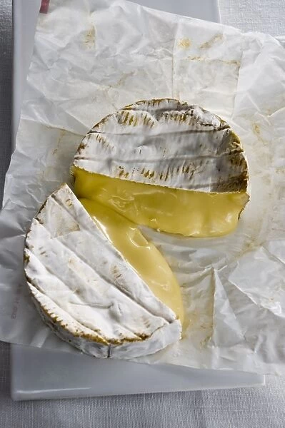 Whole round Camembert cheese cut in half showing ripe runny interior credit: Marie-Louise