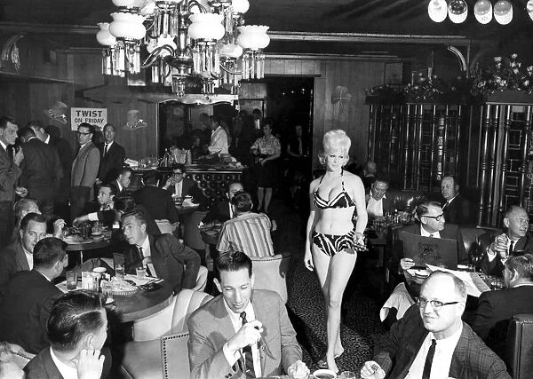A scanty clad waitress is the high light attracting the attentions of a male audience