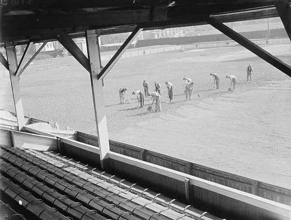 Seen from the spectator stands, workers on the pitch at the Northfleet football ground