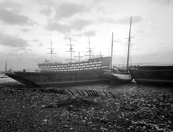 Shipping run aground on the shore in front of HMS Worcester on the River Thames off