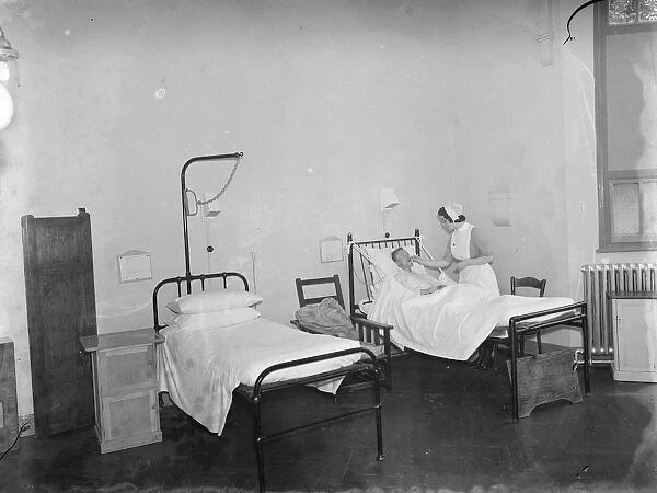 The Sidcup Cottage Hospital in Kent. A nurse tends to a patient in the mens ward