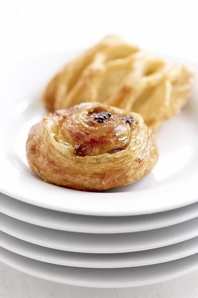 Small danish pastries on stack of white plates credit