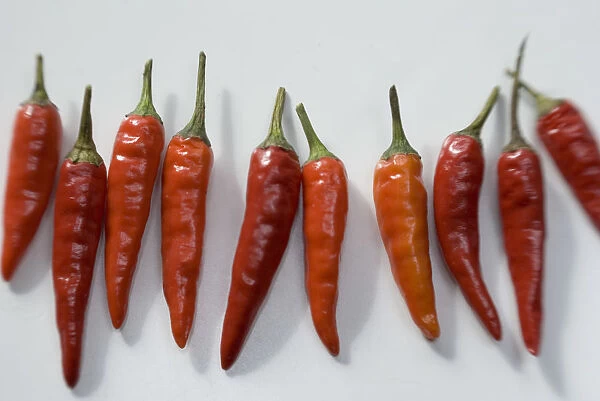 Small hot birds eye chilli peppers arranged on white surface. credit: Marie-Louise