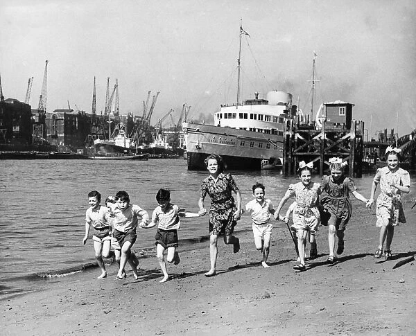 Summer at last, children running on the beach by the Tower of London. The pleasure