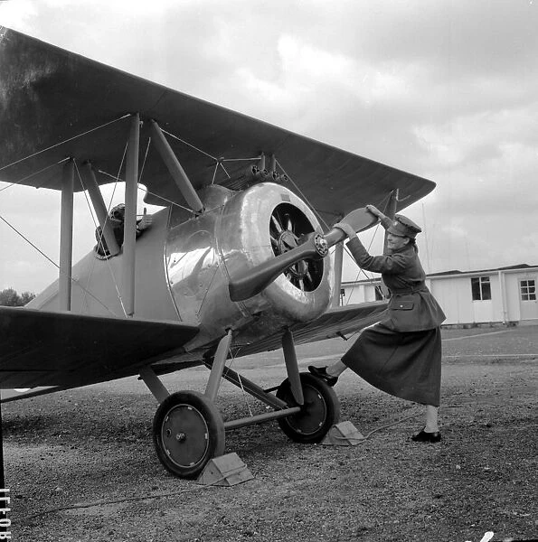 Swinging the propeller of a Sopwith Camel Plane is Irene Griffiths wearing the old