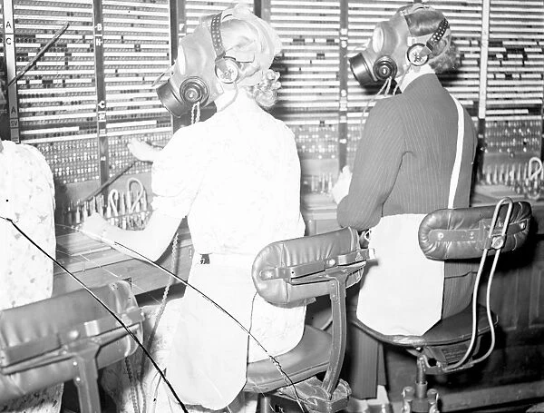 Telephone girls learn to carry on as usual in gas masks. Telephone girls are being