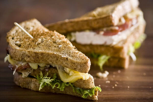 Toasted club sandwich with chicken, cheese, tomatoes, and lettuce on brown bread