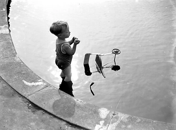 Toddler and his trike in the water. 1933