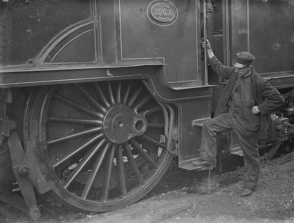 A train engineer looks at one of the large engine wheels after being derailed at Swanley