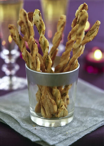 Twisted cheese straws in silver rimmed glass in candlelit party setting credit