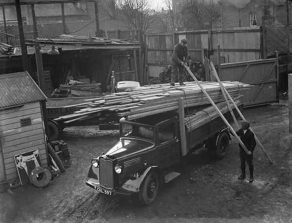 A Walter Lane Bedford lorry loads up with planks of wood at their sawmill in Sidcup