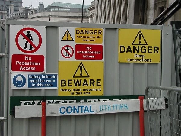 Warning notices on a metal screen outside a construction site in Trafalgar Square