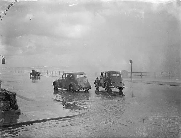 Wind, rain and sea lash Hastings. Heavy seas bursting over cars passing along the