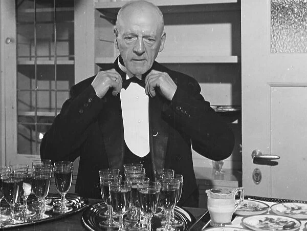 A wine waiter fixes his bow tie. undated
