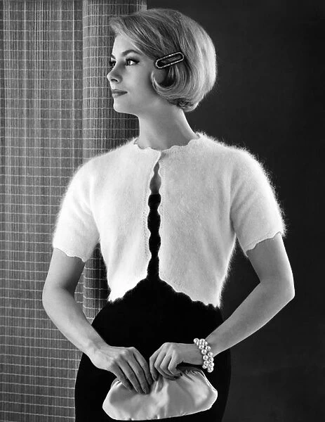 Woman models an angora knitted bolero top over a black party dress, in her hair