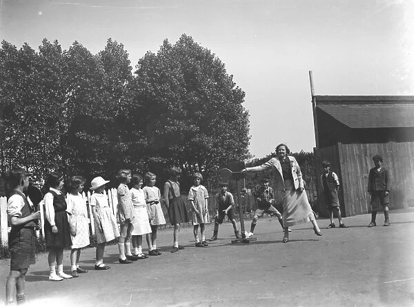 A woman playing stoolball with children in Hartley, Kent. 1937