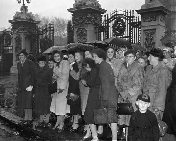Women with umbrellas and macintoshes waited outside Buckingham Palace in the rain
