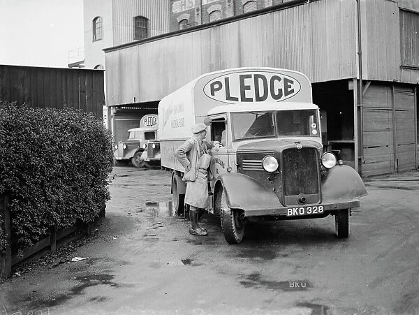 A worker chats to the driver of a loaded Bedford truck belonging to Pledge & Son Ltd