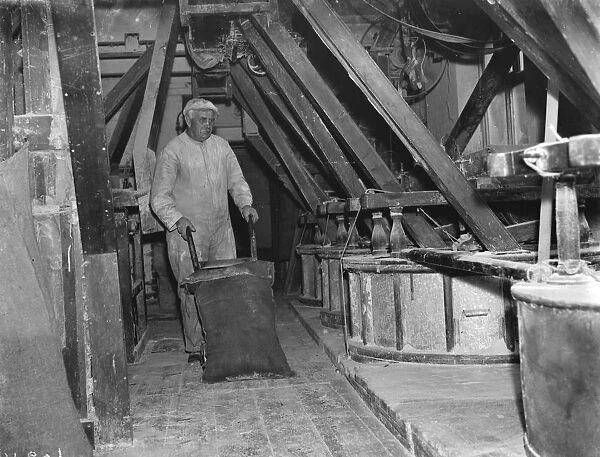 A worker shifting a sack with a trolley at the old fashioned flour mill in Erith, London