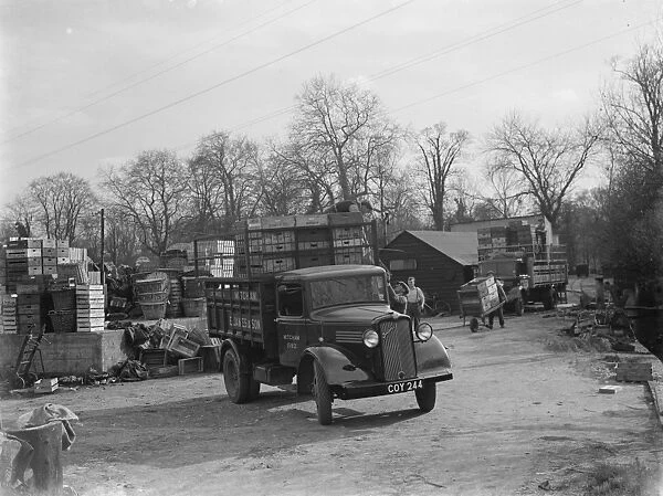 Workers loading wooden crates onto a Bedford truck belonging to E James and Son