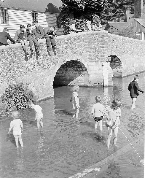 Young children paddle in the ford by the Eynsford humpback bridge over the River