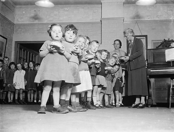 Young children receive their buns from the Guy Fawkes Charity. 1935