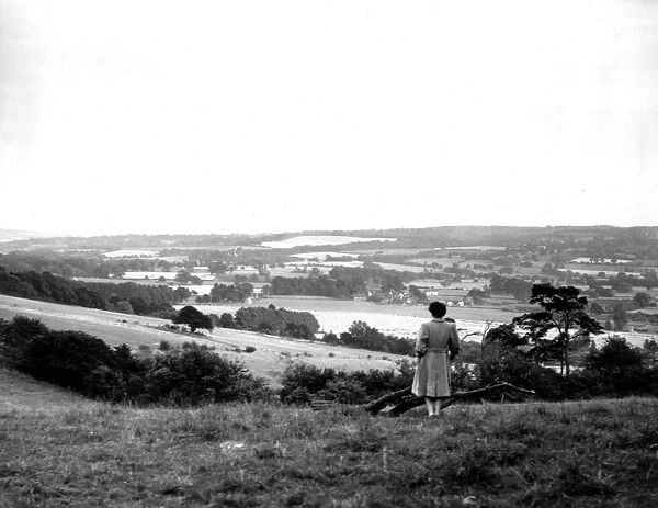 A young woman admires a view across the Weald of Kent