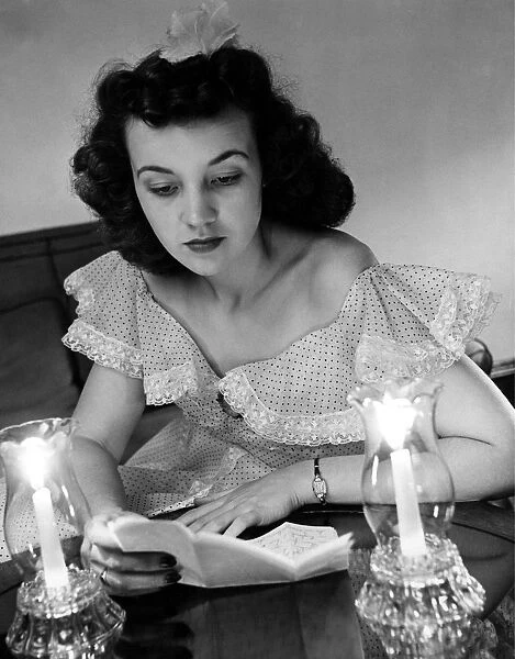 Young woman reading a letter by candlelight from her sweetheart in the American Forces in England