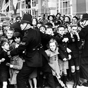 14 October 1938 Crowds of children, held back by policemen, cheering Queen Mary