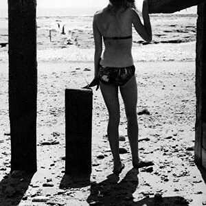 Ann Powys - A woman in the 1960s in a bikini on the beach wearing a straw sun hat