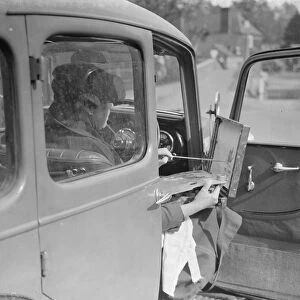 Artist painting at the wheel of his car in Eynsford, Kent. 1938