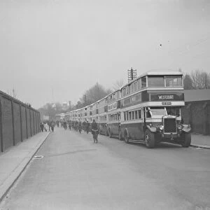 Buses parked on the road outside Chatham dockyard. Dock workers cycling past