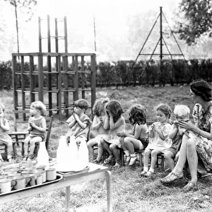 The children from St Leonards Day Nursery sit in a line with their nursery teacher