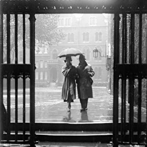A couple walking in the rain under an umbrella in Deans Yard, Westminster Abbey
