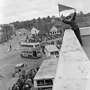Derby Day in Epsom, Surrey. A Bus official signalling the double - decker buses