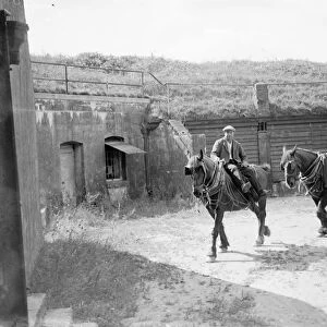 Farm workers ride work horses past an old Fort on their farm at Farningham, Kent