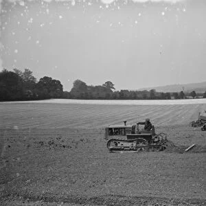 A farmer and his tank track tractor, harrow a field 1936