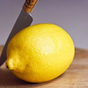 Whole fresh lemon with knife on cutting board credit: Marie-Louise Avery / thePictureKitchen