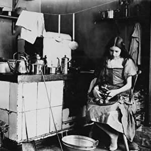 A girl peeling apples in a kitchen. c. 1908