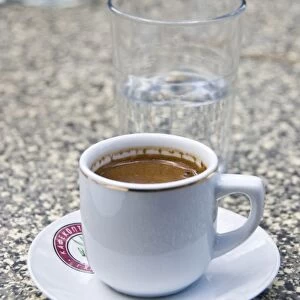 Greek coffee and glass of water on table of restaurant in Cyprus hills. credit