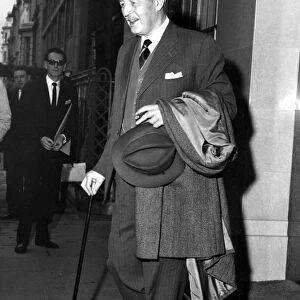 Harold Macmillan with walking stick and cigar leaving Claridges Hotel, West London