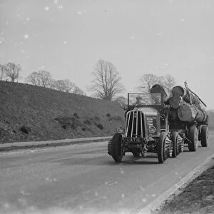 Heavy load of logs being towed by a tractor. 1935