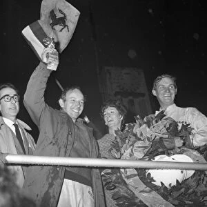 John Surtees smiles as he waves his trophy from the Victory Rostrum after he had